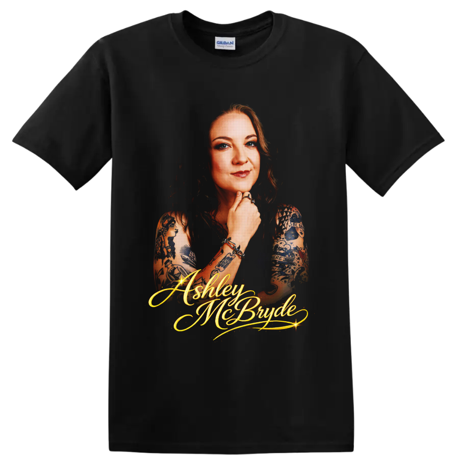 Ashley McBryde portrait with tattoo art and glowing gold script lettering on a Black T Shirt
