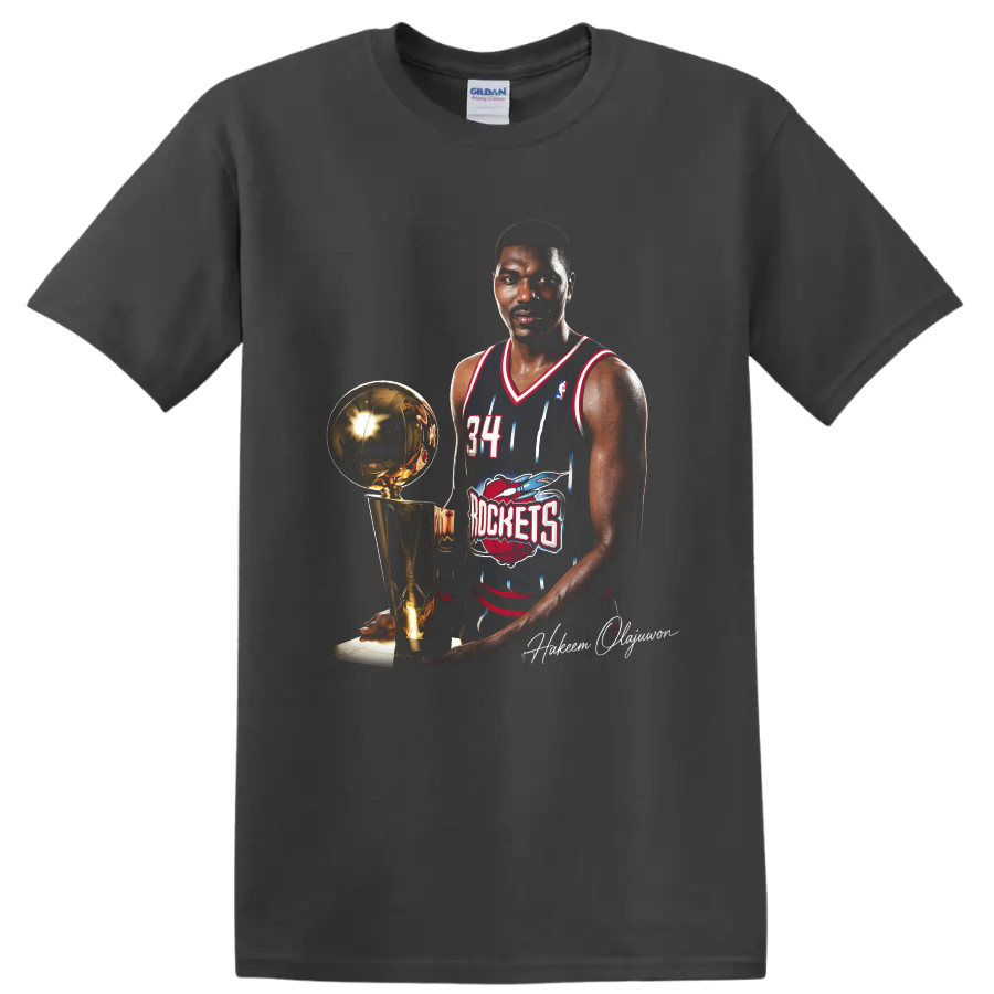 Hakeem Olajuwon in Houston Rockets No. 34 uniform beside championship trophy on a Charcoal T Shirt