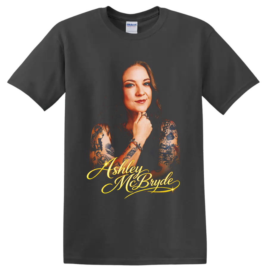 Ashley McBryde portrait with tattoo art and glowing gold script lettering on a Charcoal T Shirt